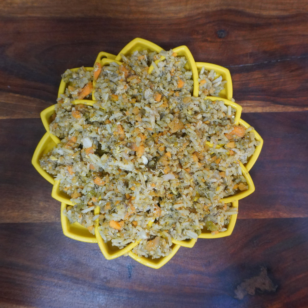 A yellow Mandala Maze bowl filled with a chicken, rice, yams, peas, carrots, sardines, egg, salmon oil and micro-nutrients. 